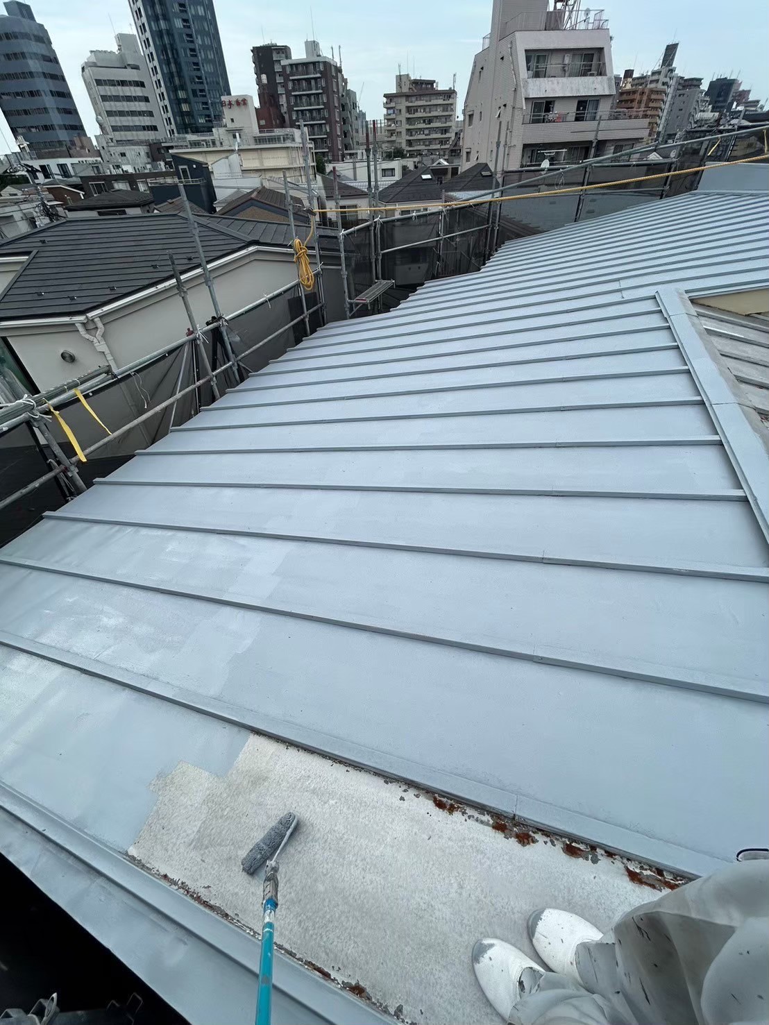屋根の塗装作業を進める職人